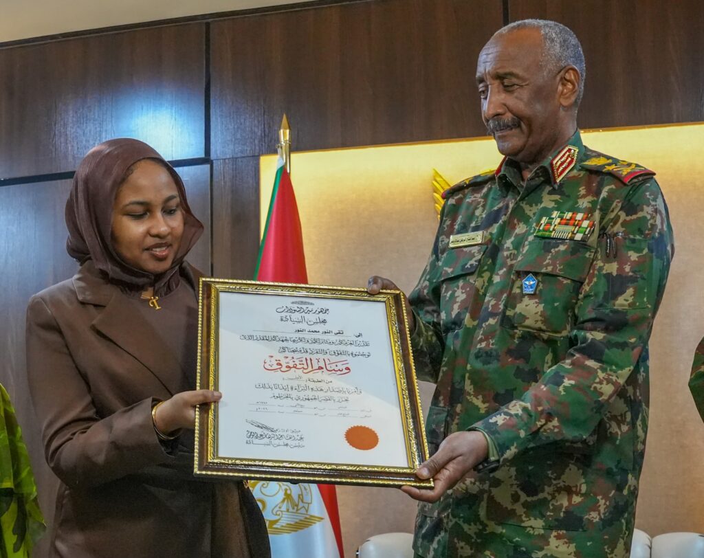 الطالبة تقى النور محمد تتسلم وسام التفوق من رئيس مجلس السيادة في مطار الخرطوم الدولي